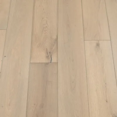 A photograph of a sand-coloured plank flooring. The planks feature a light, sandy hue with natural wood grain patterns, providing a warm and inviting appearance.